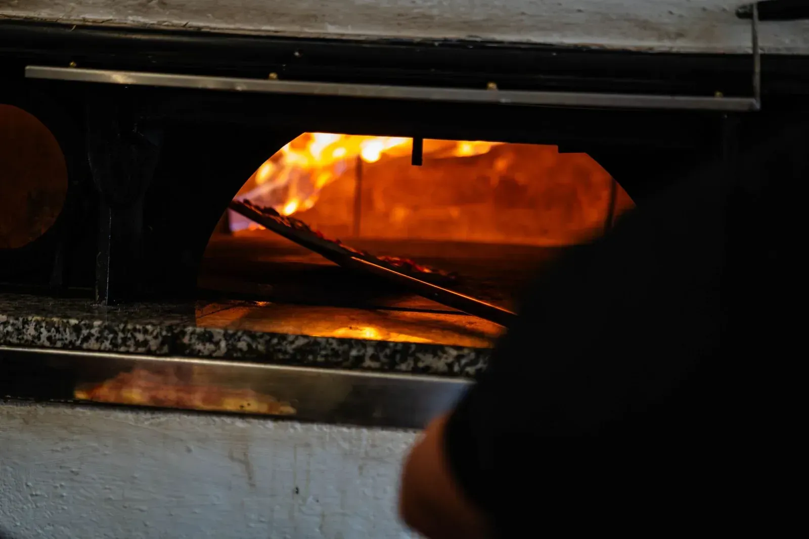 Holzofenhandwerk bei der Zubereitung von Pizza im Ristorante Colosseo